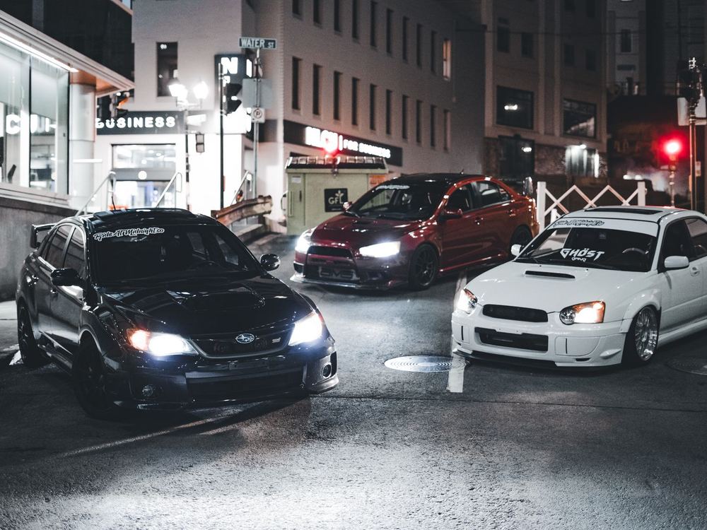 Modified cars lit up on a city street at night