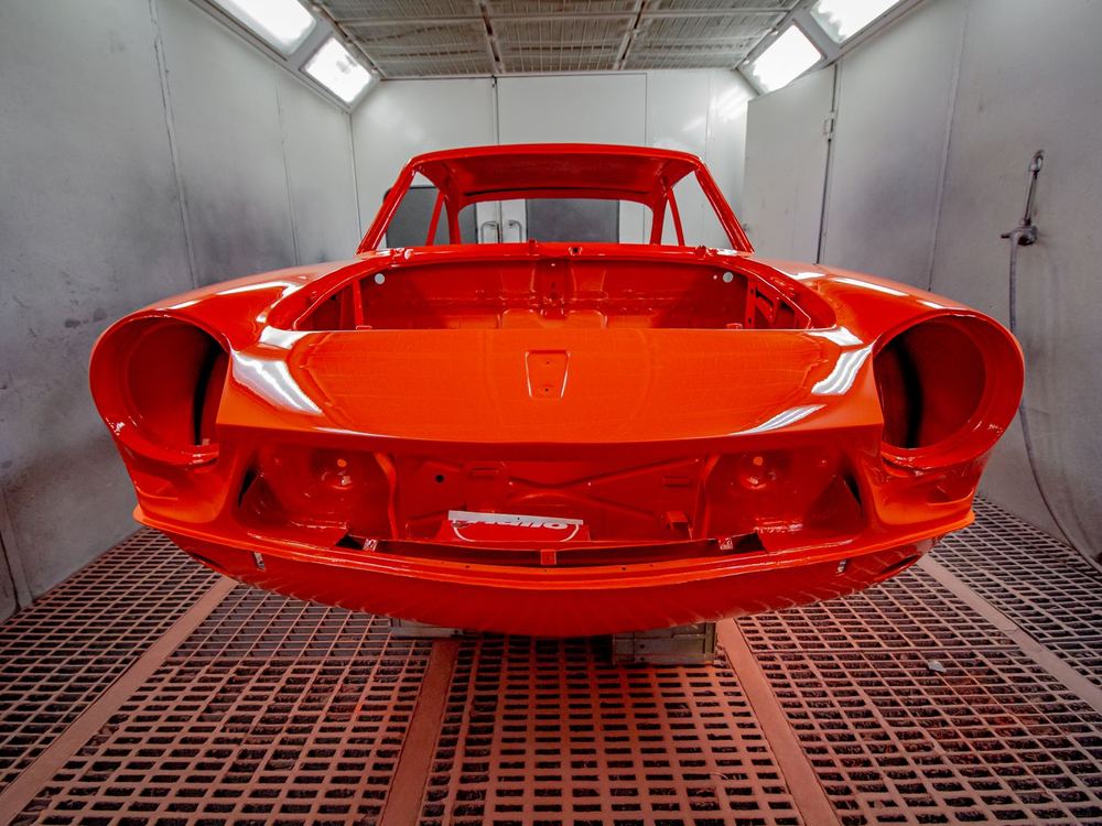 Freshly sprayed red car body inside a paint booth