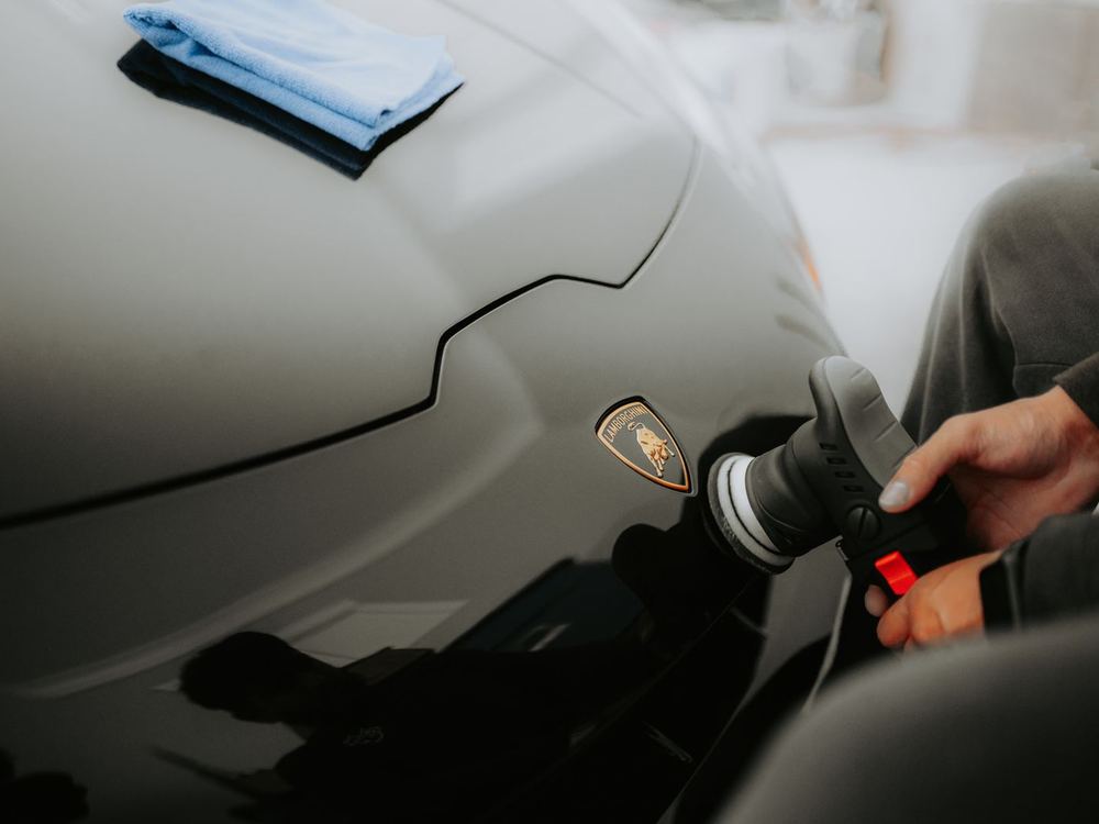 Machine polisher working across a supercar panel