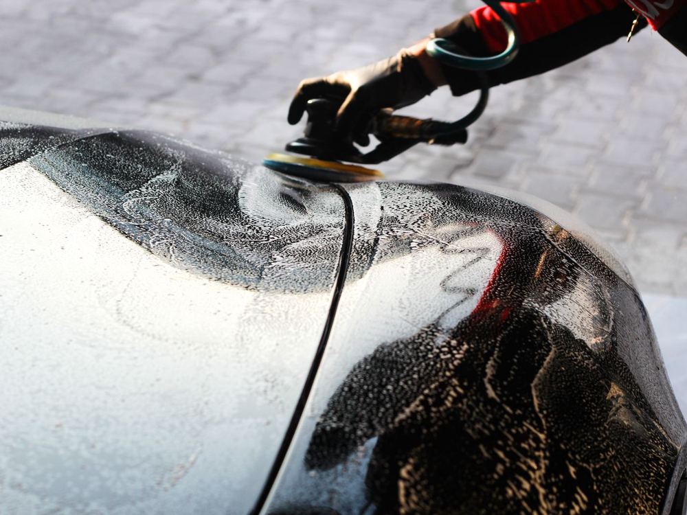 Polisher gliding over a wet, reflective panel
